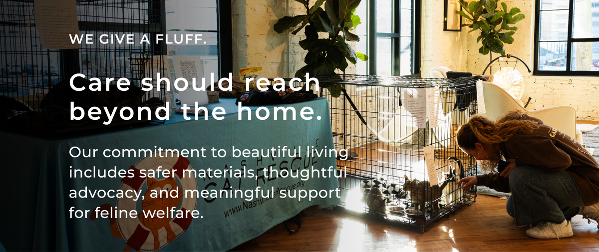 An image of a cat adoption event with text reading "WE GIVE A FLUFF. Care should reach beyond the home. Our commitment to beautiful living includes safer materials, thoughtful advocacy, and meaningful support for feline welfare."
